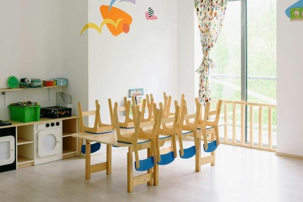 A bright kindergarten classroom with small wooden tables and chairs