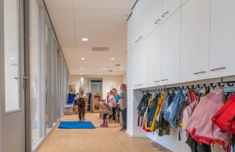 A primary school corridor lined with coat hooks and children's bags