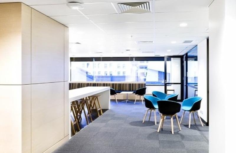 A tertiary campus common area with grey carpet and blue chairs